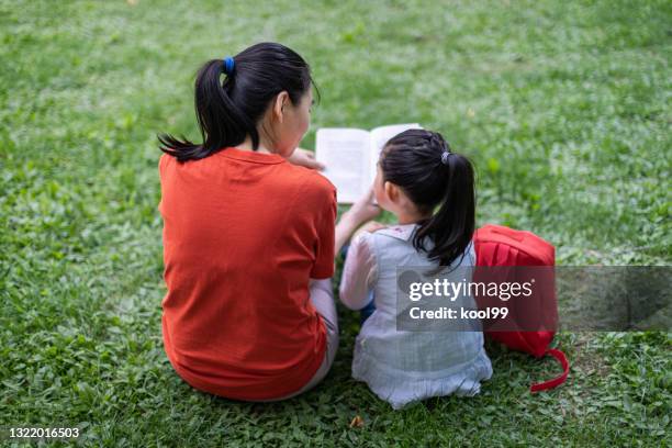 little girl and mother reading book - read book outside young woman stock pictures, royalty-free photos & images