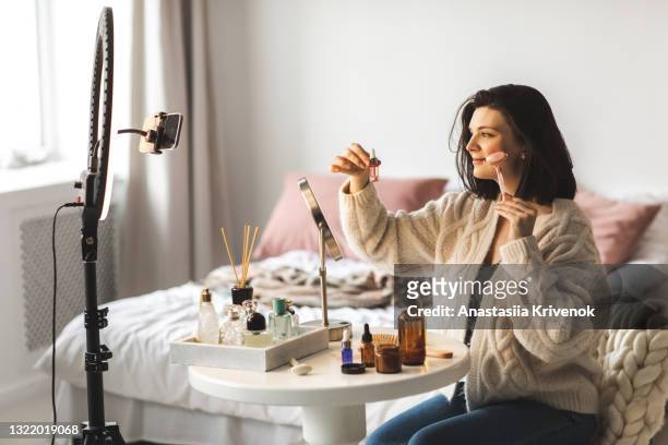 woman sitting at a table giving herself a face massage with a rose quartz roller. - mobile massage table stock pictures, royalty-free photos & images