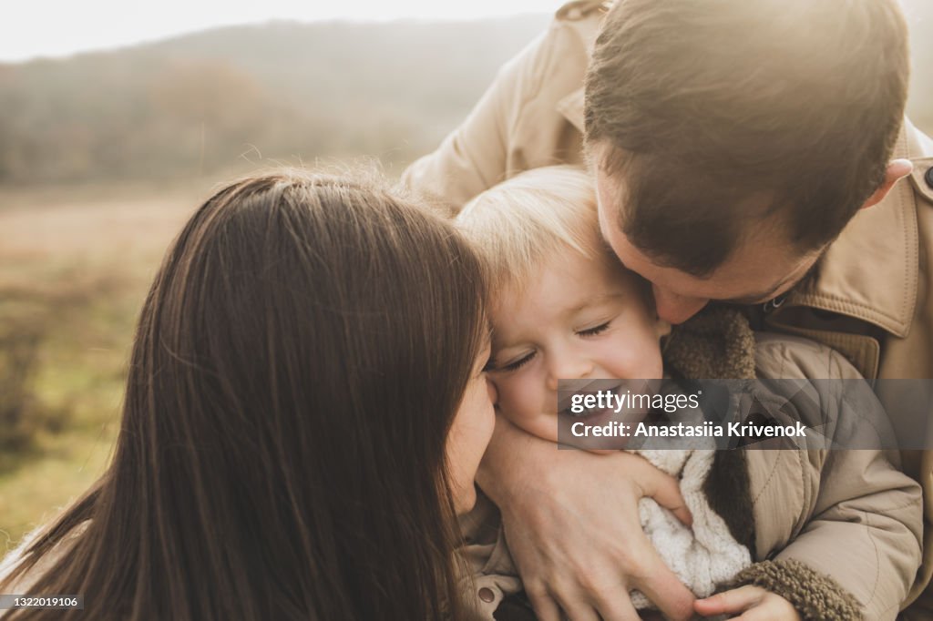 Mom and Dad cuddling their little daughter, laughing, close up