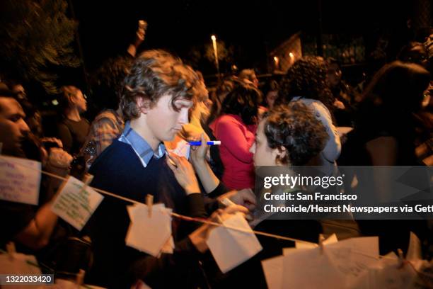 Tsama Pineda and Elizabeth Cspedes , both of San Francisco, use each other's shoulder to write a message to hang with other messages at an alter on...