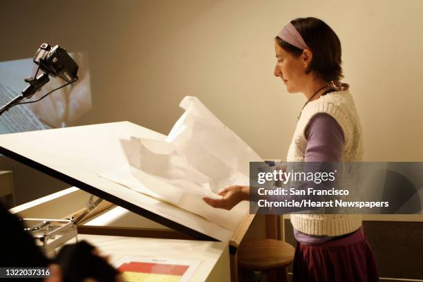 Julie Seltzer covers up samples of her writing at the display where she will be writing out the Torah at the "As It Is Written: Project 304,805"...