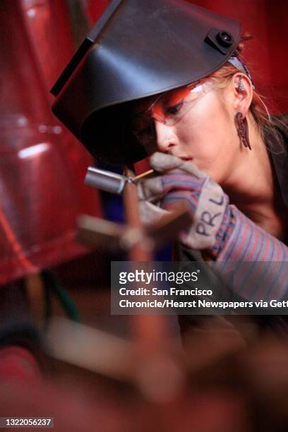 Stanford University student Andrea Stein takes a close look while welding a piece of metal onto the spine of a whale sculpture she is creating with...