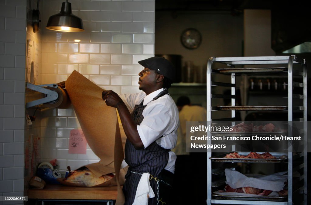 City College of San Francisco student Norman Nesby Jr. tears a sheet of paper to wrap some meat in as he works at his internship at The Local Butcher Shop on Thursday, February 20, 2014 in Berkeley, Calif.