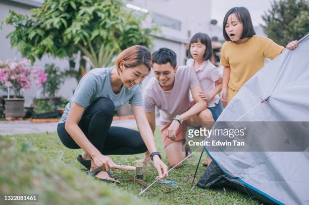 madre cinese asiatica allevare tenda da campeggio con l'aiuto della sua famiglia nel cortile di casa durante il fine settimana - picchetto da tenda foto e immagini stock