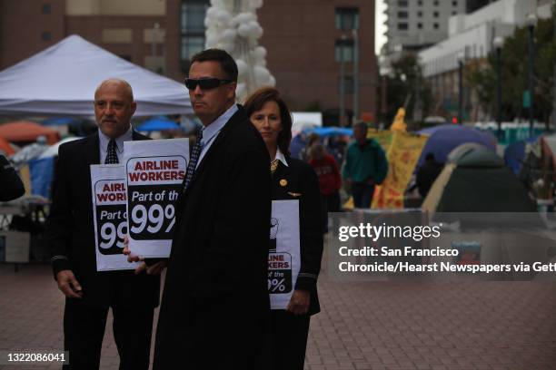 American Airlines flight attendants Brian Berger, Larry Salas and Julie Hedrick carry signs stating that they are part of the 99% at Justin Herman...