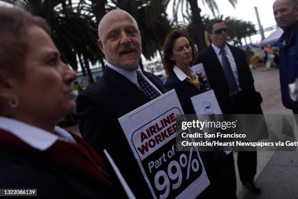 American Airlines flight attendants Heidi Cain , Brian Berger, Julie Hedrick and Larry Salas carry signs stating that they are part of the 99% at...