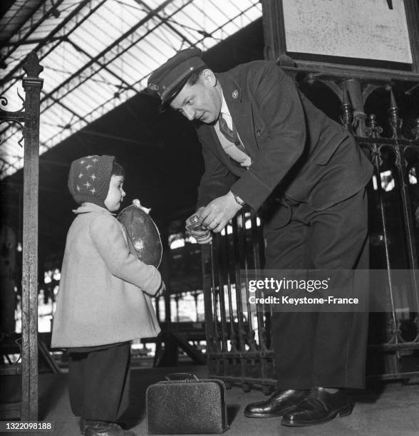 Petite fille présentant son oeuf de Pâques à un contrôleur dans une gare de Paris, le 7 avril 1950.