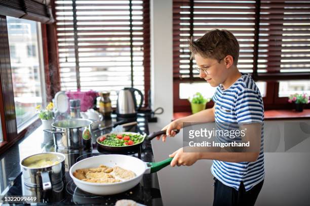 tiener die maaltijd voor familie helpt voorbereidingen te bereiden - boy kitchen stockfoto's en -beelden