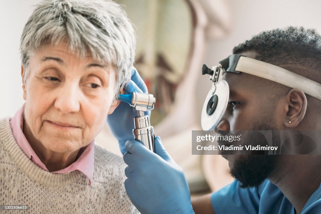 Close up of a mature adult woman has ears checked by doctor at routine medical appointment