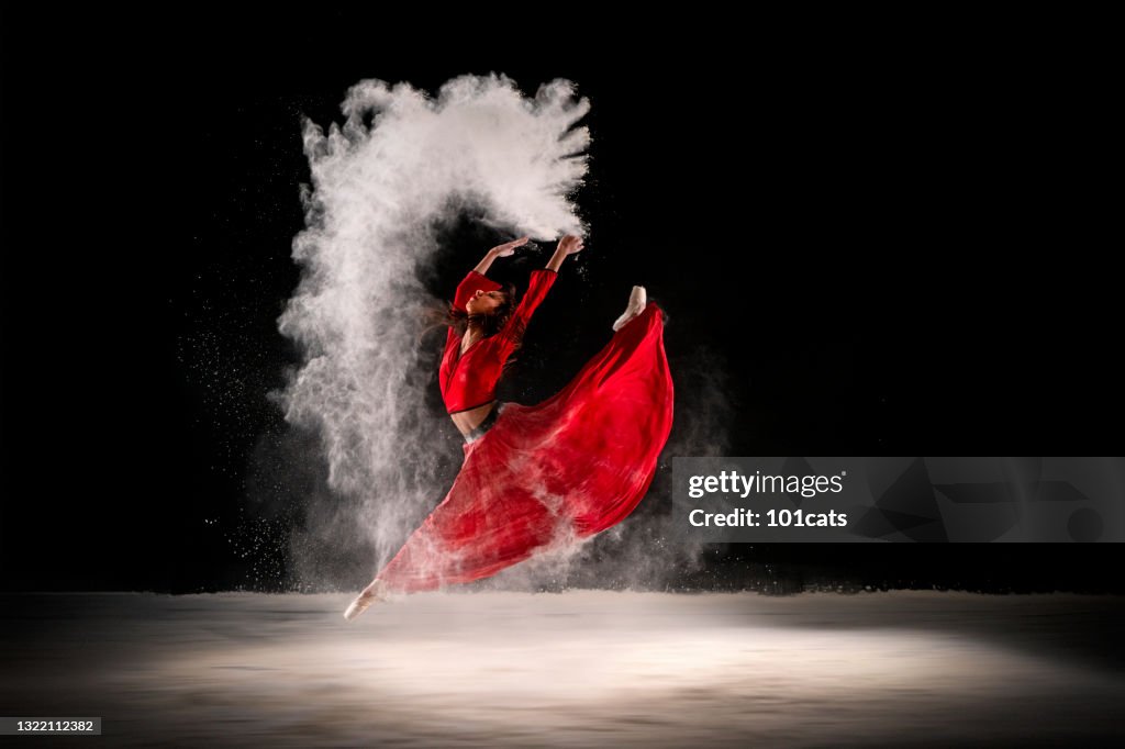 Ballerina in red dress, dancing with dust