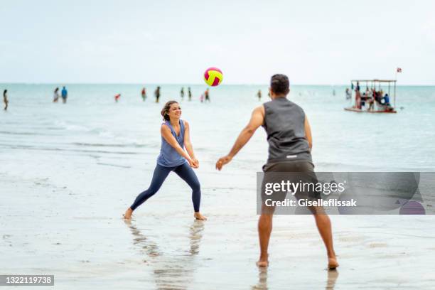 couple playing volleyball on the beach - beach volleyball friends stock pictures, royalty-free photos & images