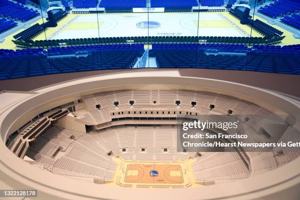 An arena model is displayd in front of screens projecting an image of the arenaáat a Warriors sales office adjacent to the future Chase Centeráon...