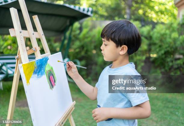 kleines kind junge malerei im garten - body color stock-fotos und bilder