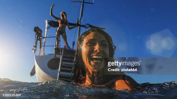 summer vacations: friends diving from a yacht sailboat at sea - camera boat stock pictures, royalty-free photos & images