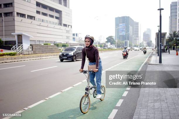 asian young hijab woman, riding her bike, bicycle lane - single lane road stock-fotos und bilder