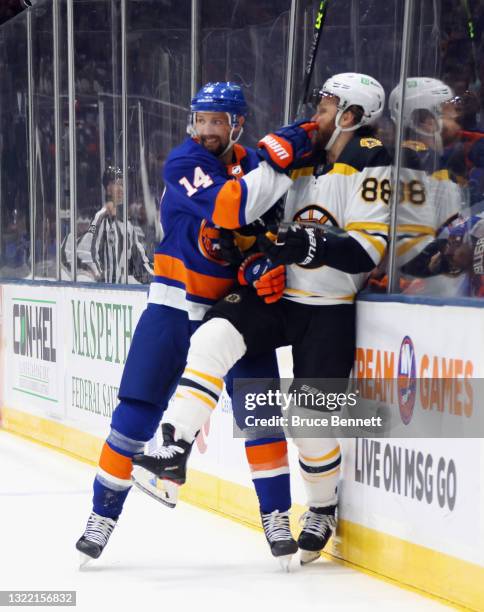 David Pastrnak of the Boston Bruins is checked into the boards by Travis Zajac of the New York Islanders during the first period in Game Four of the...