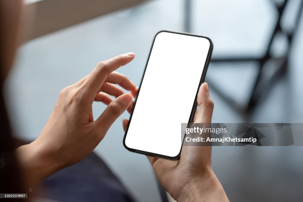 Close-up de um homem de negócios segurando uma tela branca do smartphone está em branco o fundo está desfocado. maquete.