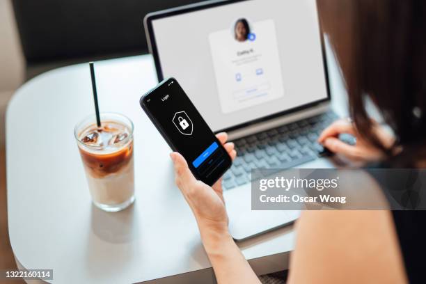young business woman logging in online security system on laptop with mobile app on smartphone - cubierta fotografías e imágenes de stock