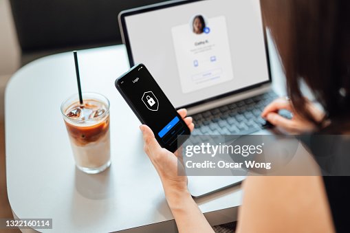 Young Business Woman Logging in Online Security System On Laptop With Mobile App On Smartphone Young Business Woman Logging in Online Security System On Laptop With Mobile App On Smartphone
