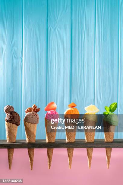 assorted ice cream waffle cones in a row colorful different flavor on pink and blue wood - mint chocolate chip ice cream scoop stock pictures, royalty-free photos & images