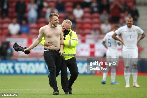Pitch invader is directed off of the pitch by stadium security during the international friendly match between England and Romania at Riverside...