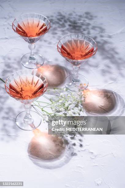 rose or rosé cocktail three cups pink color on white whitewashed table with colorful shadows - raspberry cocktail stock pictures, royalty-free photos & images