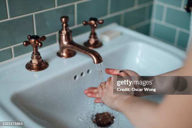 cropped shot of young woman washing hands at the bathroom sink - women with health faucet stock pictures, royalty-free photos & images