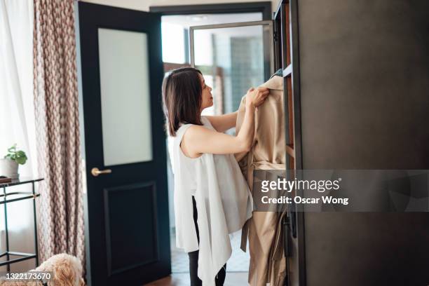 young woman choosing outfits from wardrobe, getting ready to go out - clothes wardrobe stock-fotos und bilder