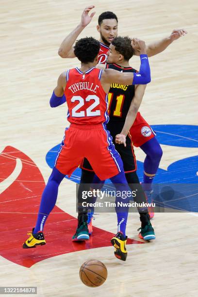 Trae Young of the Atlanta Hawks passes between Ben Simmons and Matisse Thybulle of the Philadelphia 76ers during the fourth quarter during Game One...