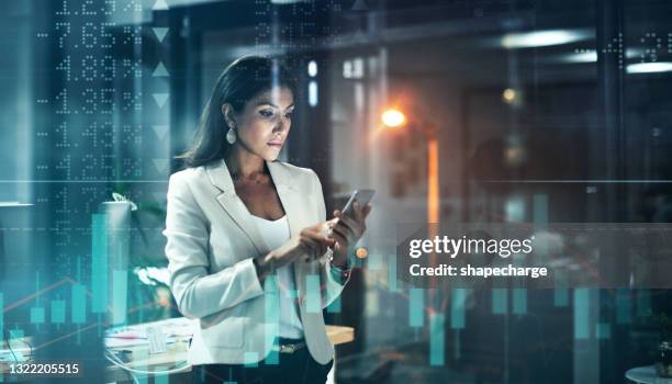 foto mejorada digitalmente de una atractiva empresaria usando un teléfono celular superpuesta sobre un gráfico que muestra los altibajos del mercado de valores - certificado de una acción fotografías e imágenes de stock