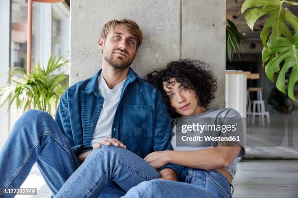 tired couple leaning on column while sitting on floor at home apartment - tired couple stock pictures, royalty-free photos & images