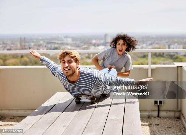 young woman holding boyfriend leg while enjoying on terrace - lying on front stock pictures, royalty-free photos & images