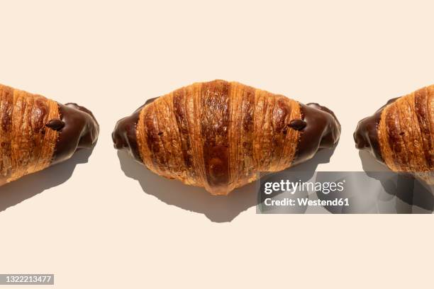 tempting chocolate croissants on beige background - croissant stockfoto's en -beelden