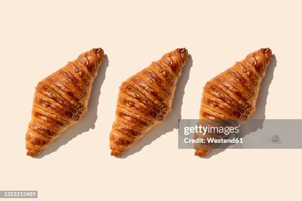 butter croissants in a row on beige background - croissant viennoiserie stock-fotos und bilder