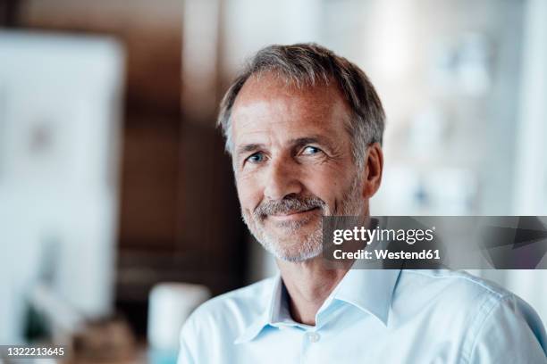 senior businessman smiling in office - 60 64 jahre stock-fotos und bilder