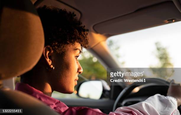young woman driving car during sunny day - mujer conduciendo fotografías e imágenes de stock