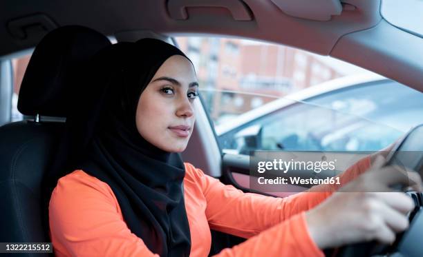 thoughtful arab woman looking away while driving car - arab driving stock-fotos und bilder