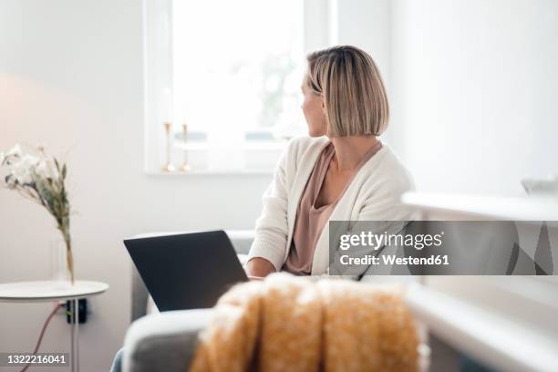 short haired woman with laptop looking away at home - looking at view stock pictures, royalty-free photos & images