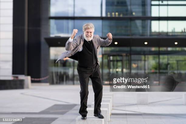 ecstatic businessman standing on concrete block in front of office building - city block ストックフォトと画像