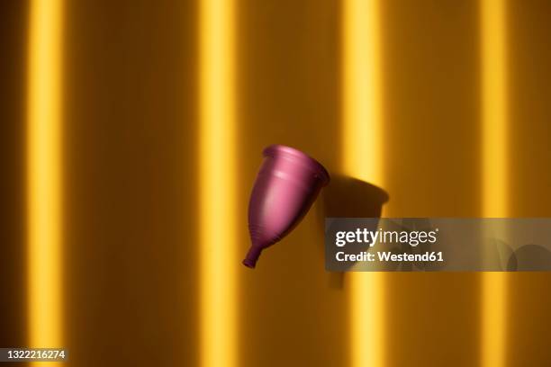 menstrual cup against shadowed yellow background - menstrual cup stock pictures, royalty-free photos & images