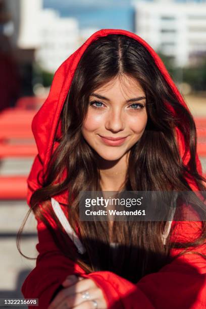 smiling blue eyed teenage girl wearing red hood jacket on sunny day - hood clothing stock pictures, royalty-free photos & images