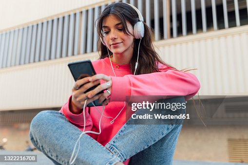 Beautiful teenage girl wearing headphones while using smart phone Beautiful teenage girl wearing headphones while using smart phone
