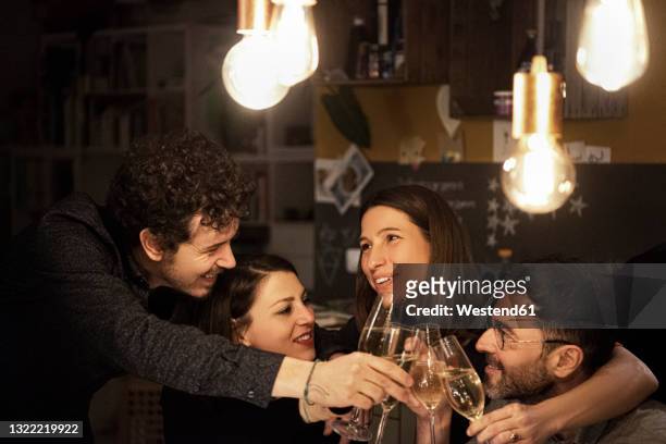 happy male and female friends raising toast during birthday celebration at home - four people foto e immagini stock
