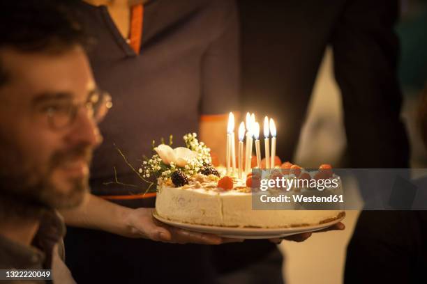 birthday cake held by mature woman by male friend in birthday party at home - cheesecake imagens e fotografias de stock