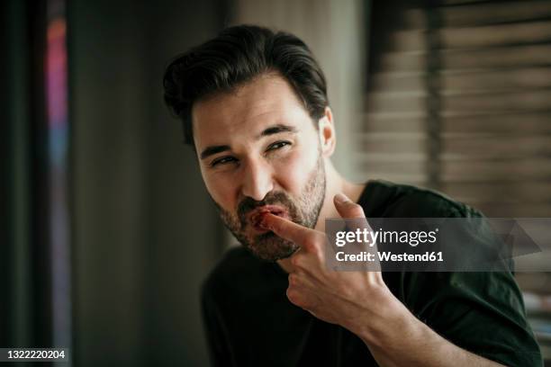 happy man licking finger while looking away - licking finger stock pictures, royalty-free photos & images