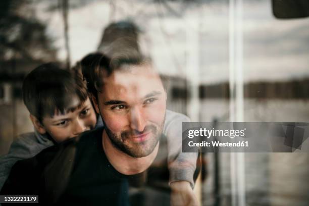 father and son looking through window - kid looking through window stock pictures, royalty-free photos & images