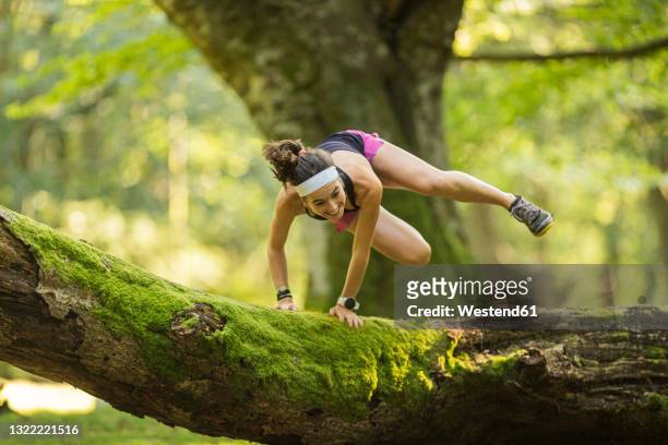 confident woman jumping over fallen tree in forest - extreme depth of field stock pictures, royalty-free photos & images