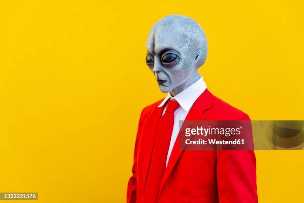 portrait of man wearing alien costume and bright red suit - alien stockfoto's en -beelden