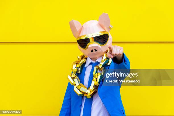 man wearing vibrant blue suit, pig mask and large golden chain pointing toward camera - bling bling imagens e fotografias de stock