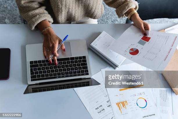 businesswoman using laptop while analyzing data at office - finance report stockfoto's en -beelden